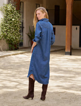 Load image into Gallery viewer, Model wearing a long-sleeve maxi denim shirtdress from behind, paired with brown cowboy boots