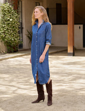 Load image into Gallery viewer, Model wearing a midi-length denim button-front shirtdress with rolled sleeves and brown knee-high boots