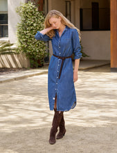 Load image into Gallery viewer, Model wearing a belted midi-length denim shirtdress with long sleeves and brown cowboy boots