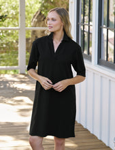 Load image into Gallery viewer, Model wearing a black short-sleeve henley mini dress with collar on an outdoor porch