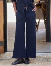 Load image into Gallery viewer, Model wearing wide-leg cropped navy sweatpant trousers with boat shoes, hands in pockets