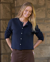 Load image into Gallery viewer, Woman wearing a navy button-front cropped sweatshirt cardigan with long sleeves and white buttons