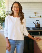 Load image into Gallery viewer, Woman wearing a white button-front sweatshirt cardigan with long sleeves in a kitchen setting