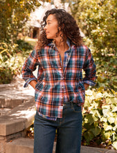 Load image into Gallery viewer, Woman wearing a relaxed plaid flannel button-up shirt with rolled sleeves in a garden setting