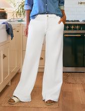Load image into Gallery viewer, Model wearing wide-leg white trouser sweatpants with chambray shirt and sandals in kitchen setting