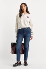 Load image into Gallery viewer, Model wearing straight-leg mid-rise indigo jeans with a cream sweatshirt and black loafers