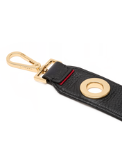 Load image into Gallery viewer, Close-up detail of black leather grommet keychain fob with gold hardware and red accent