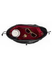Load image into Gallery viewer, Overhead interior view of black leather bag with red lining, keys, sunglasses, and travel mug