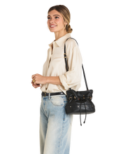 Load image into Gallery viewer, Model wearing cream blouse and jeans carrying Hammitt Gianna drawstring bucket crossbody bag