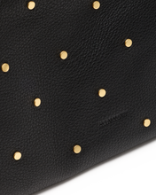 Load image into Gallery viewer, Close-up detail of black pebbled leather bag with scattered gold dome studs and embossed logo