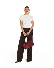 Load image into Gallery viewer, Model holding Hammitt Meredith Medium burgundy leather handbag with gold hardware details