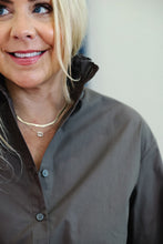 Load image into Gallery viewer, Woman wearing a button-front shirt in dark mocha with layered gold necklaces, close-up detail view