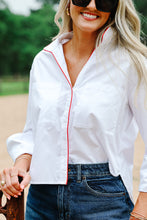 Load image into Gallery viewer, Woman wearing a white button-down shirt with red piping trim, paired with dark denim jeans