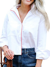 Load image into Gallery viewer, Woman wearing a cropped white button-down shirt with red piping trim and front pockets