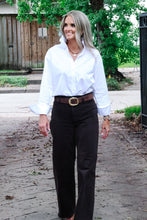 Load image into Gallery viewer, Woman wearing white ruffle collar button-down shirt tucked into dark wide-leg trousers outdoors
