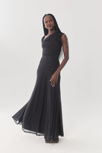 Load image into Gallery viewer, Model wearing a sleeveless black ruched mesh maxi gown with flared skirt and fringe detail