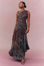 Load image into Gallery viewer, Model wearing a sleeveless ruched maxi dress with multicolor floral print and flowing skirt