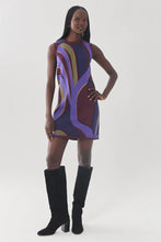 Load image into Gallery viewer, Model wearing a sleeveless mini shift dress with abstract retro swirl pattern, styled with tall black boots