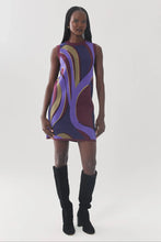 Load image into Gallery viewer, Sleeveless mini shift dress with bold swirling retro abstract pattern in purple and burgundy, styled with black knee-high ...