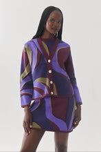 Load image into Gallery viewer, Model wearing a bold abstract swirl-patterned knit cardigan and matching mini skirt set