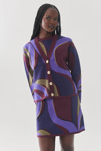 Load image into Gallery viewer, Model wearing a bold abstract-patterned knit cardigan with gold buttons and matching mini skirt