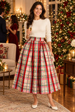 Load image into Gallery viewer, Woman wearing a festive plaid midi ball skirt paired with a cozy knit sweater at a holiday party.