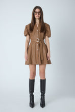 Load image into Gallery viewer, Model wearing a belted faux leather mini dress with puff sleeves and button front, styled with knee-high black boots
