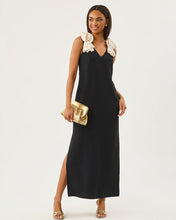 Load image into Gallery viewer, Model wearing a sleeveless black maxi dress with cream rosette shoulder straps and side slit