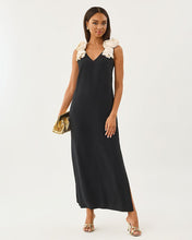 Load image into Gallery viewer, Model wearing a sleeveless black maxi dress with cream ruffled shoulder straps and a V-neckline