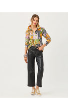 Load image into Gallery viewer, Model wearing a vibrant animal and jungle print pullover with black leather pants and gold sneakers