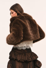 Load image into Gallery viewer, Model wearing a cropped brown faux fur jacket with lace hem detail, back view