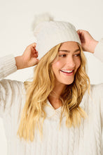 Load image into Gallery viewer, Model wearing ivory cable-knit beanie with pom-pom, paired with matching sweater