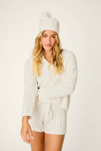 Load image into Gallery viewer, Model wearing ivory cable-knit beanie with pom-pom, matching sweater and shorts set