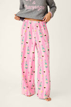 Load image into Gallery viewer, Model wearing pink striped pajama pants with champagne bottles and cupcakes print pattern