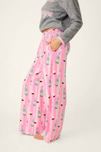 Load image into Gallery viewer, Model wearing wide-leg pink striped pants with champagne bottles and cupcakes print, side view