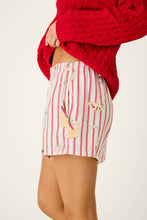 Load image into Gallery viewer, Side view of striped pajama shorts with cocktail and mistletoe print, paired with red cable knit sweater