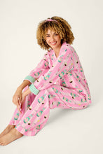 Load image into Gallery viewer, Model seated wearing pink striped pajama set with champagne bottle and cupcake print