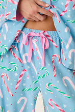Load image into Gallery viewer, Close-up detail of candy cane print pajama pants with pink drawstring tie and buttons