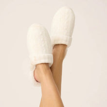 Load image into Gallery viewer, Model's feet raised wearing cozy ivory cable-knit slide slippers with plush faux fur cuff trim