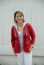 Load image into Gallery viewer, Woman smiling outdoors wearing a red blazer with grey hoodie insert and white pants