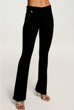 Load image into Gallery viewer, Black velvet flare pants with decorative silver buttons on high waistband, worn with strappy heels