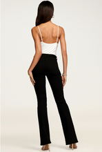 Load image into Gallery viewer, Back view of model wearing black high-rise flare jeans with white bodysuit and heeled sandals
