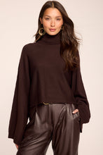 Load image into Gallery viewer, Model wearing a dark brown turtleneck cropped sweater with wide sleeves and ribbed cuffs