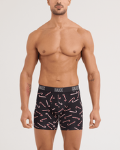 Load image into Gallery viewer, Male model wearing black Saxx boxer briefs with festive candy cane pattern and branded waistband