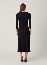 Load image into Gallery viewer, Back view of a model wearing a ribbed knit midi dress with three-quarter sleeves and pleated skirt