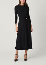 Load image into Gallery viewer, Model wearing a black knit midi dress with ribbed pleated skirt and gold buckle detail