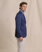 Load image into Gallery viewer, Man wearing a navy blue windowpane blazer with light trousers, side view on model