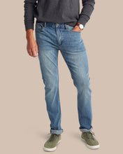 Load image into Gallery viewer, Man wearing slim-fit medium wash denim jeans with cuffed hem and green sneakers