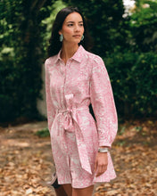 Load image into Gallery viewer, Model wearing a belted long-sleeve mini shirtdress with pink floral print in an outdoor setting