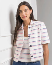 Load image into Gallery viewer, Woman wearing a short-sleeve striped tweed jacket with navy buttons over a knit top and jeans